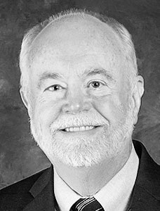 McCloskey BW-small-cropped Black and white portrait of an elderly man with a cheerful expression, sporting a white beard, and wearing a suit with a tie.